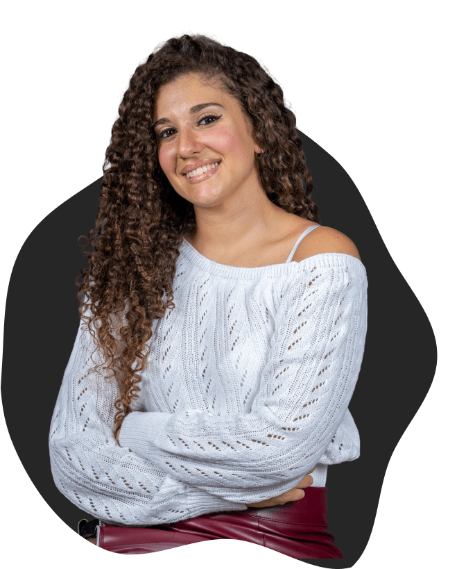 Jessica sorridente con capelli ricci e maglione chiaro, ripresa in posa naturale a braccia incrociate su sfondo scuro stilizzato.