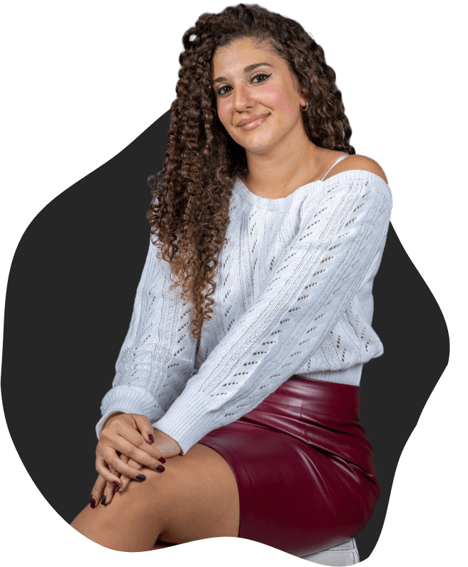 Jessica seduta che sorride in modo naturale, con maglione chiaro e gonna bordeaux, su sfondo scuro stilizzato.